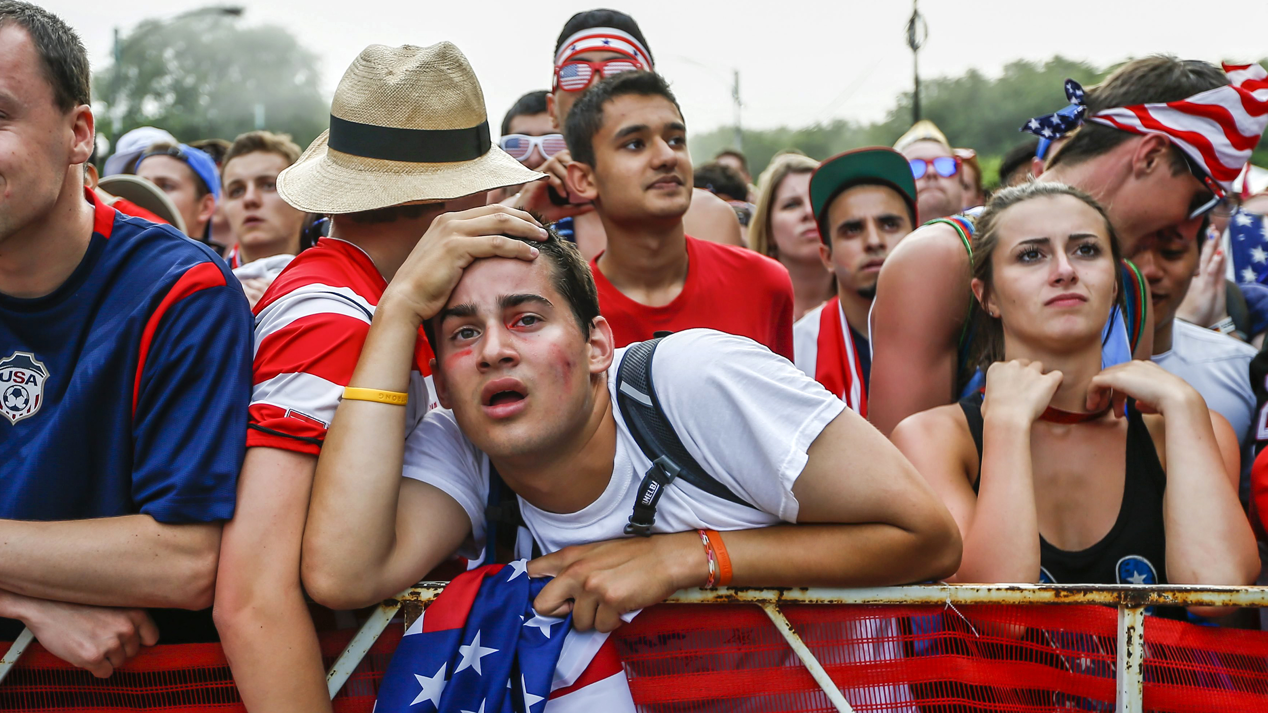 US soccer fans watching the World Cup in despair at a public screening, draped in American flags